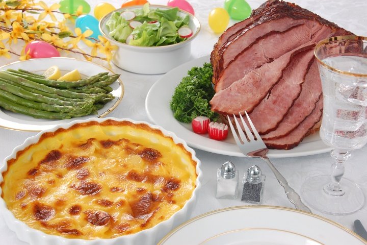 A beautifully set table for Easter dinner featuring a variety of Easter menu ideas, including ham, sides, and Easter desserts