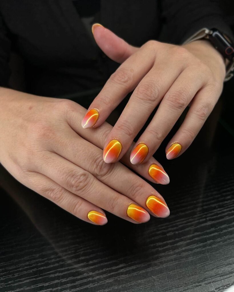 Close-up of candy corn nails with vibrant yellow, orange, and white stripes, perfect for Halloween.