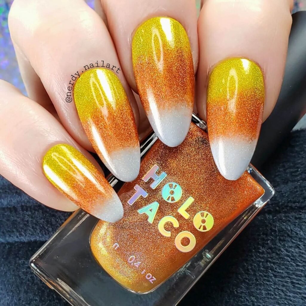 Close-up of candy corn nails with vibrant yellow, orange, and white stripes, perfect for Halloween.