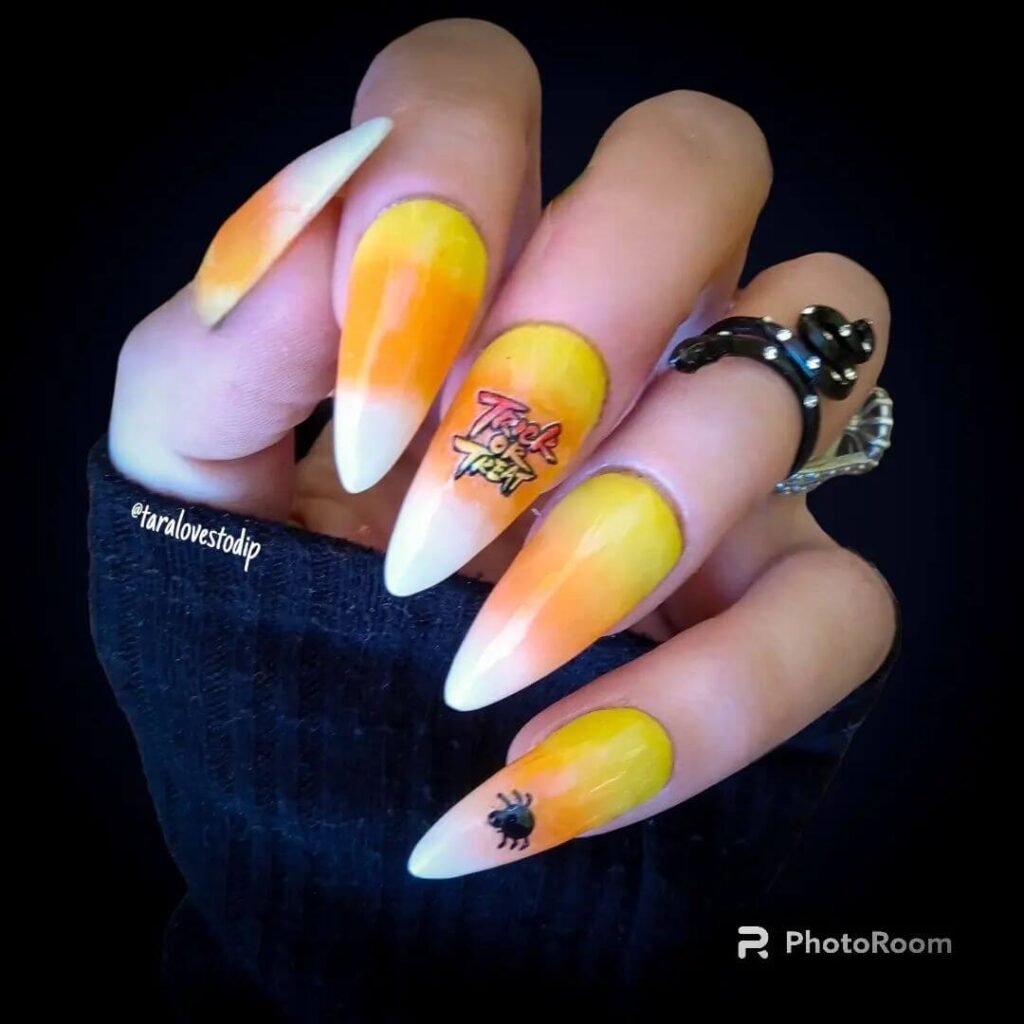 Close-up of candy corn nails with vibrant yellow, orange, and white stripes, perfect for Halloween.