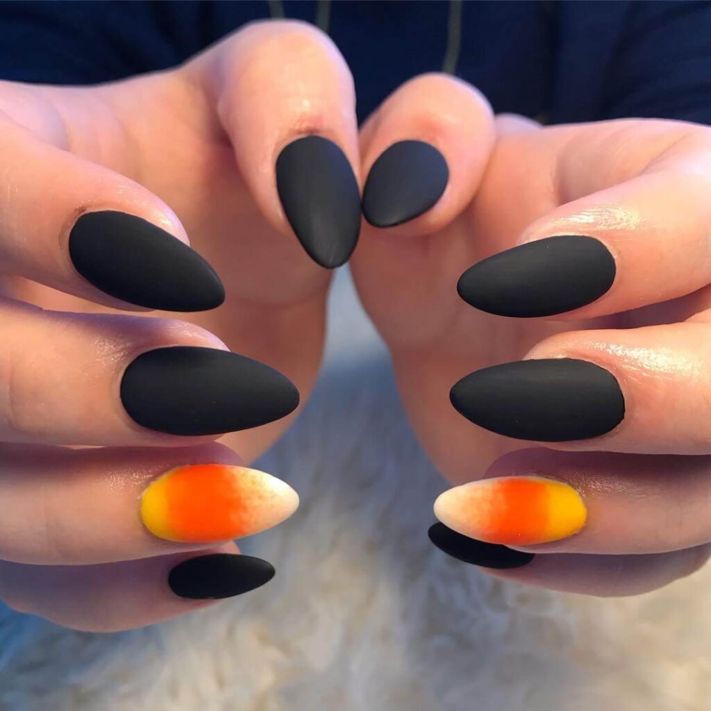 Close-up of candy corn nails with vibrant yellow, orange, and white stripes, perfect for Halloween.